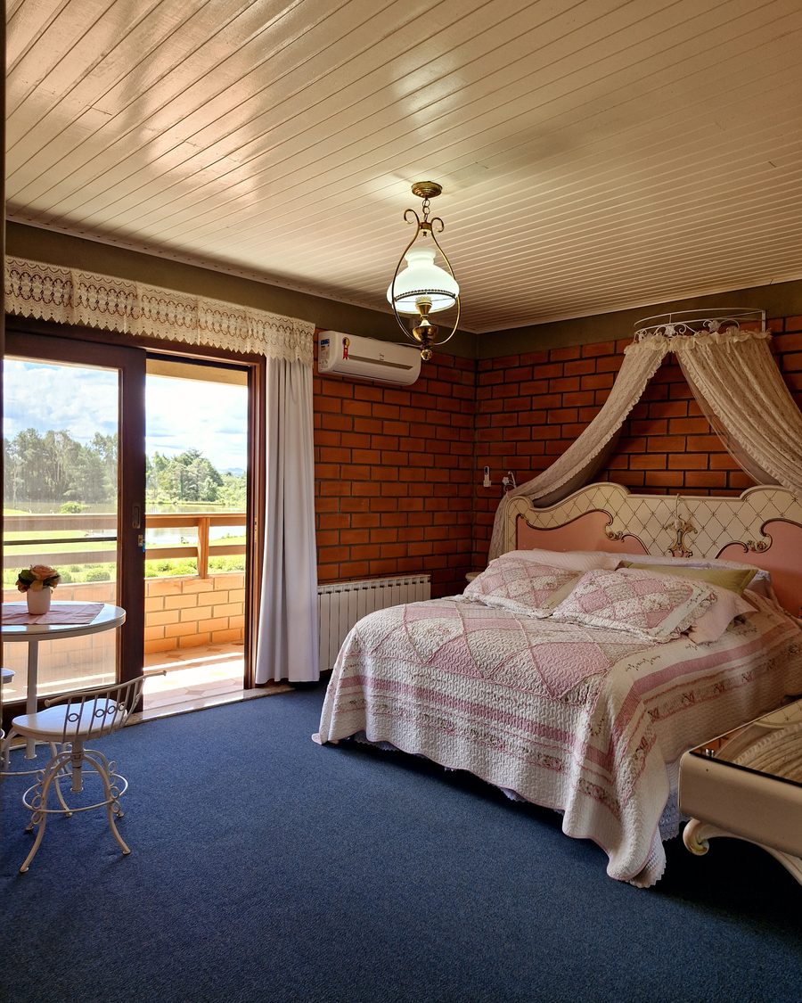 Suíte Rosa Luxo - cama com dossel e parede de tijolinho